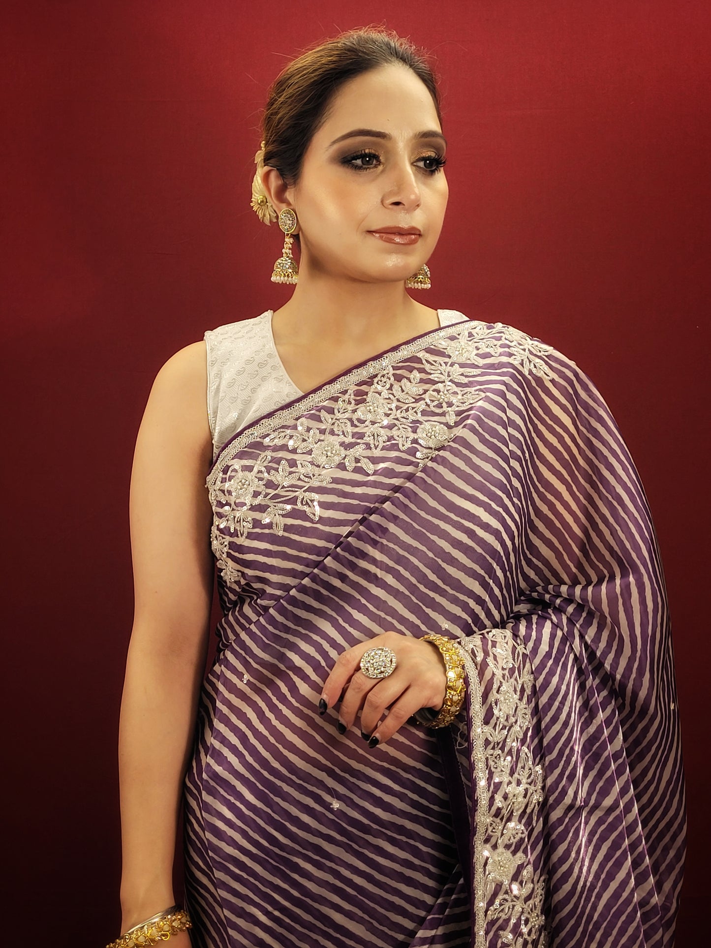 Wrap yourself in the vibrant hues of a purple & white leheriya saree crafted from sheer organza and embellished with beautiful Pitta work, a statement piece for any occasion.