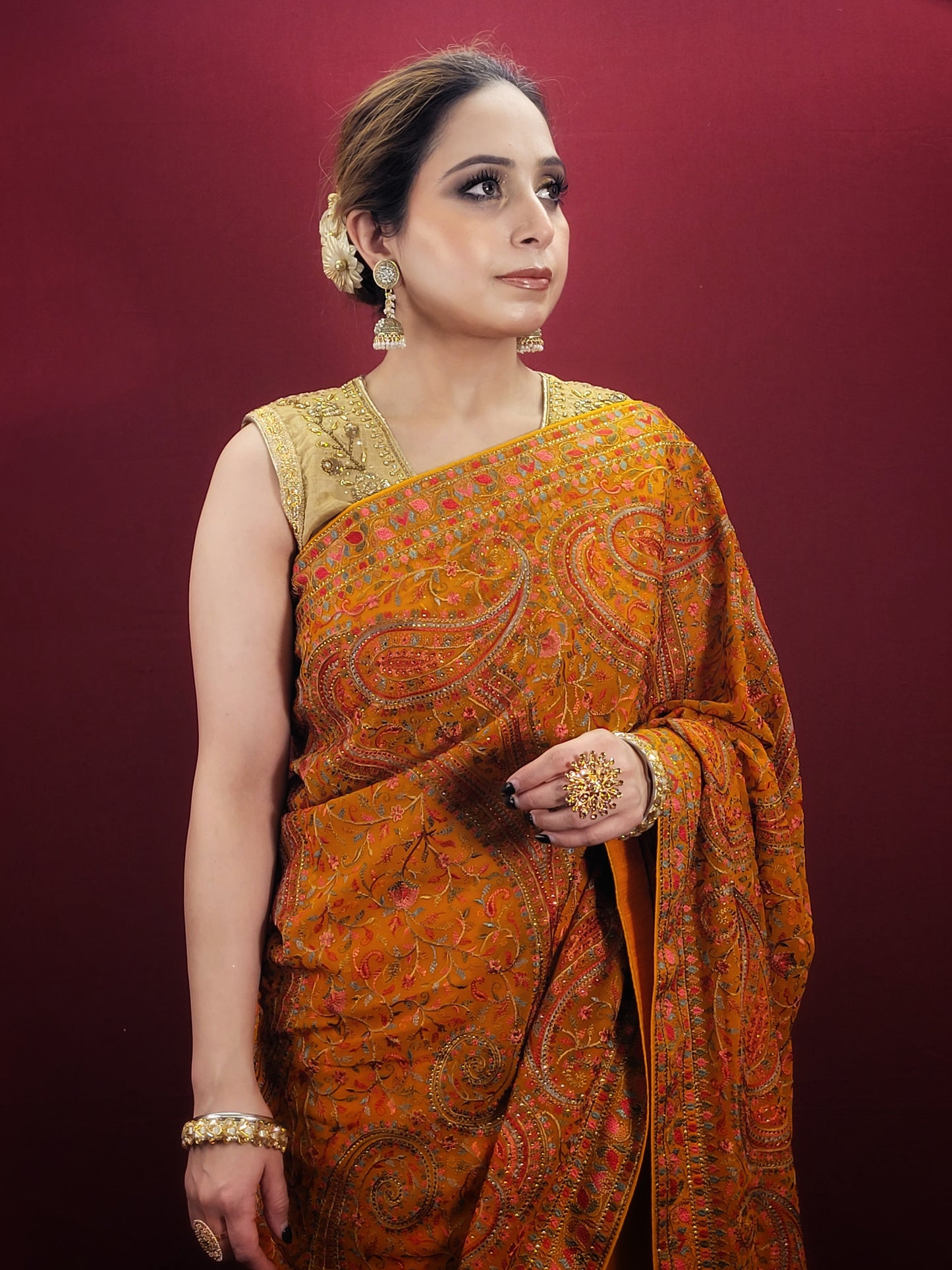 Adorn a mustard yellow georgette saree with exquisite kashmiri thread work, a versatile piece that transitions seamlessly from party wear to Puja wear.