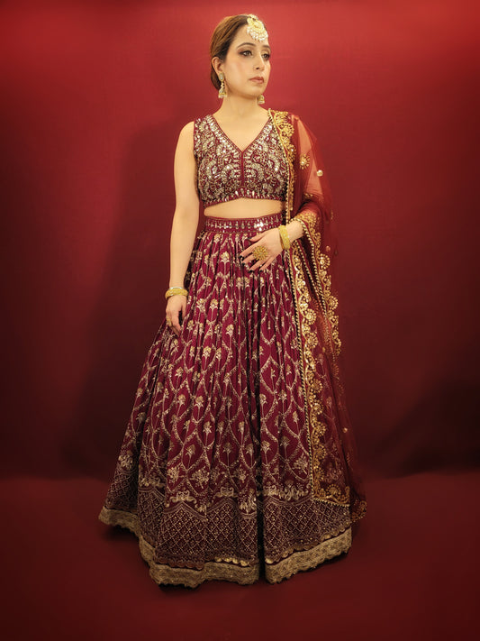 A maroon lehenga choli adorned with intricate mirror and sequins work, crafted on flowing georgette, epitomizes the grandeur of Indian ethnic wear, making it a stunning choice for wedding and bridal attire.