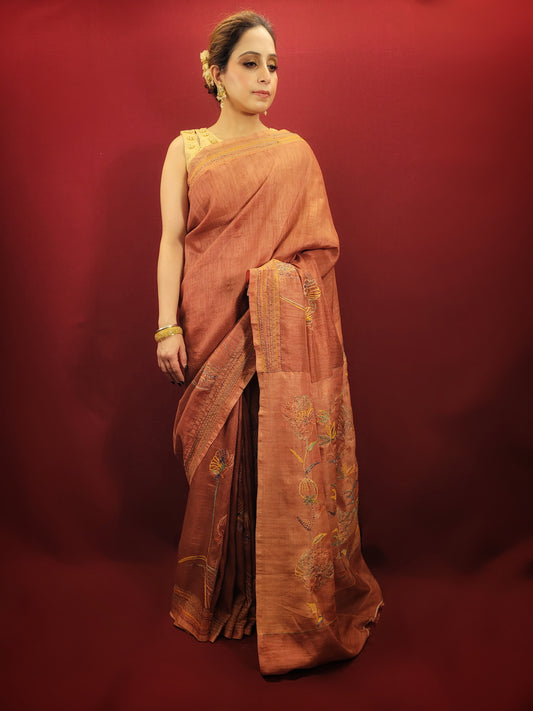 Crafted from pure silk, this saree offers a luxurious feel and a beautiful drape that flatters any figure. The rich, rust color exudes a warm and earthy elegance, perfect for making a sophisticated statement. The captivating brush print design adds a touch of modern artistry, while the delicate katha stitch highlights lend a timeless charm.