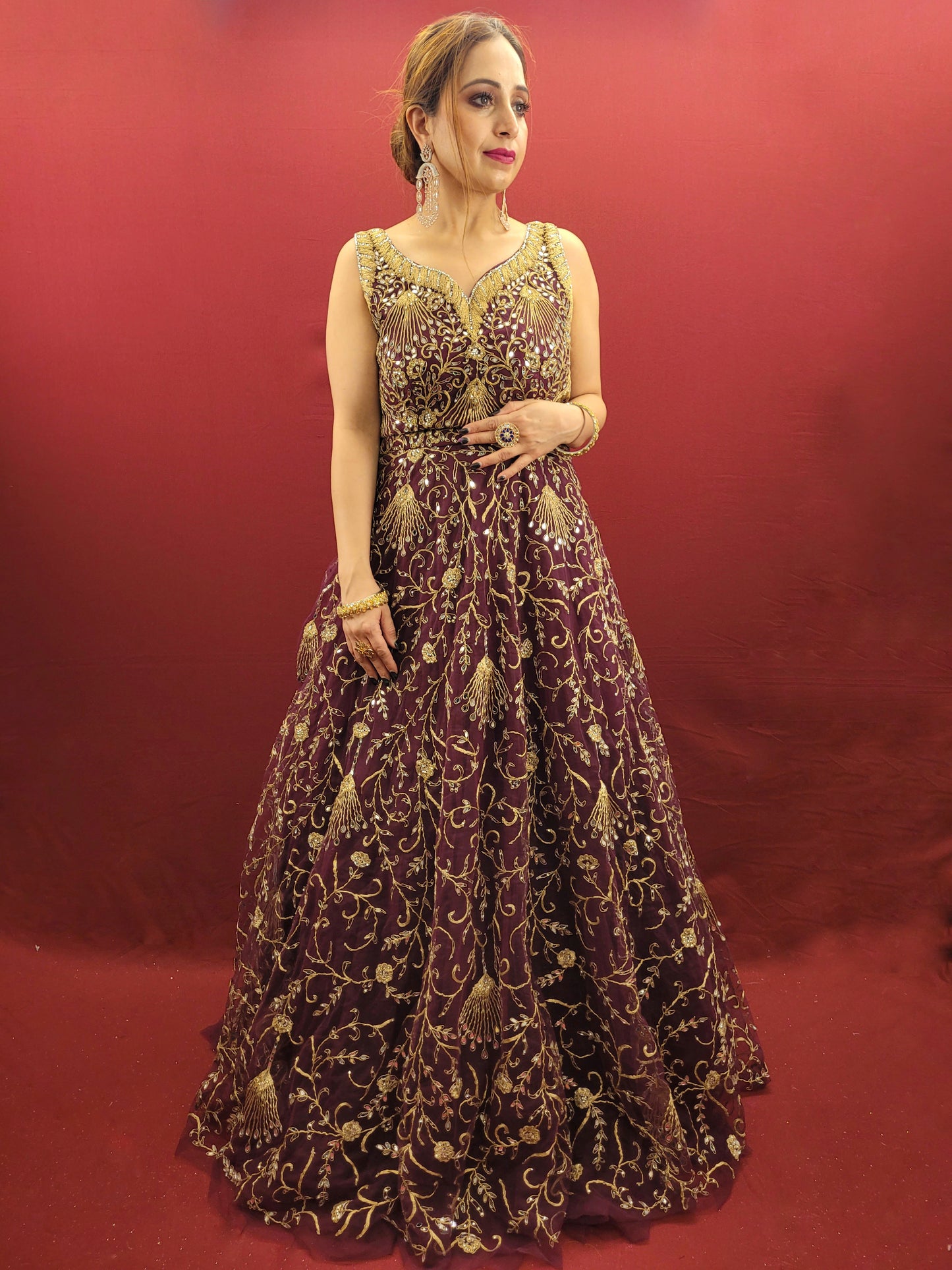 Embrace the elegance of a wine-colored gown, lavishly embellished with zari, dori and mirror work, ideal for makin a statement at engagement events and wedding parties.