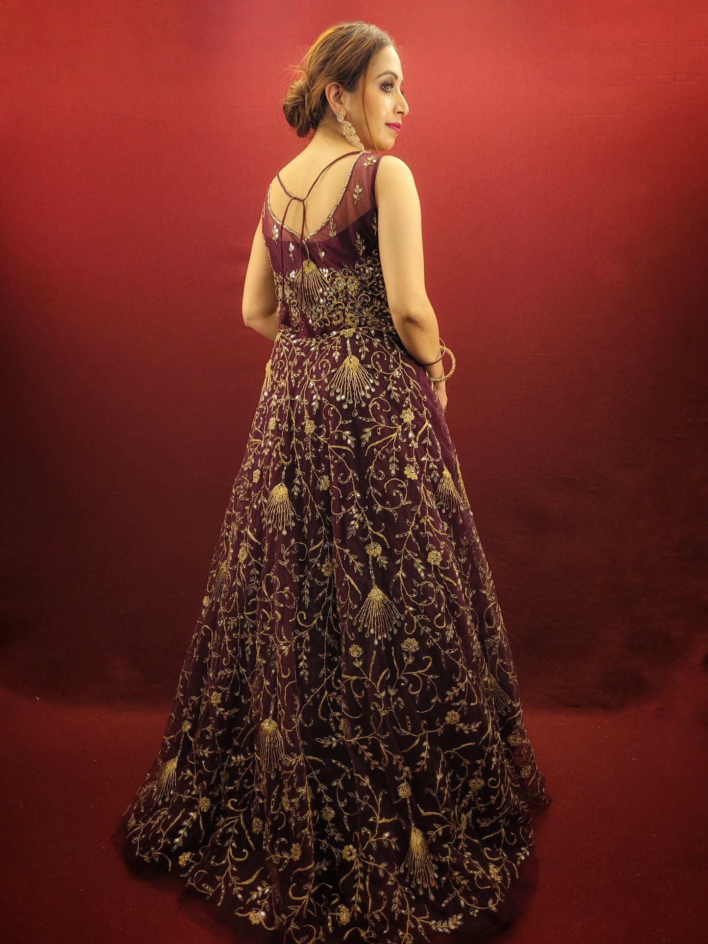Embrace the elegance of a wine-colored gown, lavishly embellished with zari, dori and mirror work, ideal for makin a statement at engagement events and wedding parties.