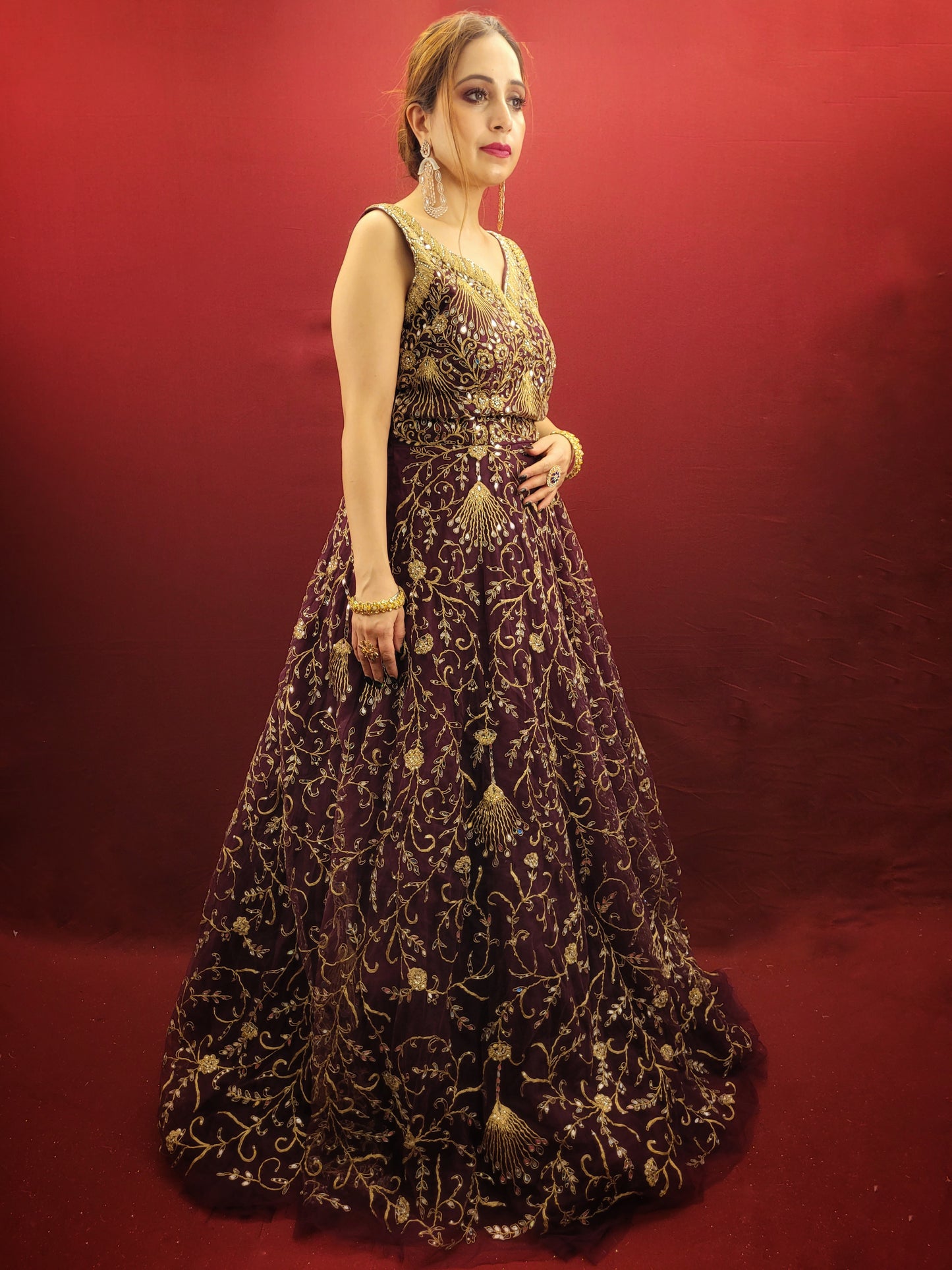 Embrace the elegance of a wine-colored gown, lavishly embellished with zari, dori and mirror work, ideal for makin a statement at engagement events and wedding parties.