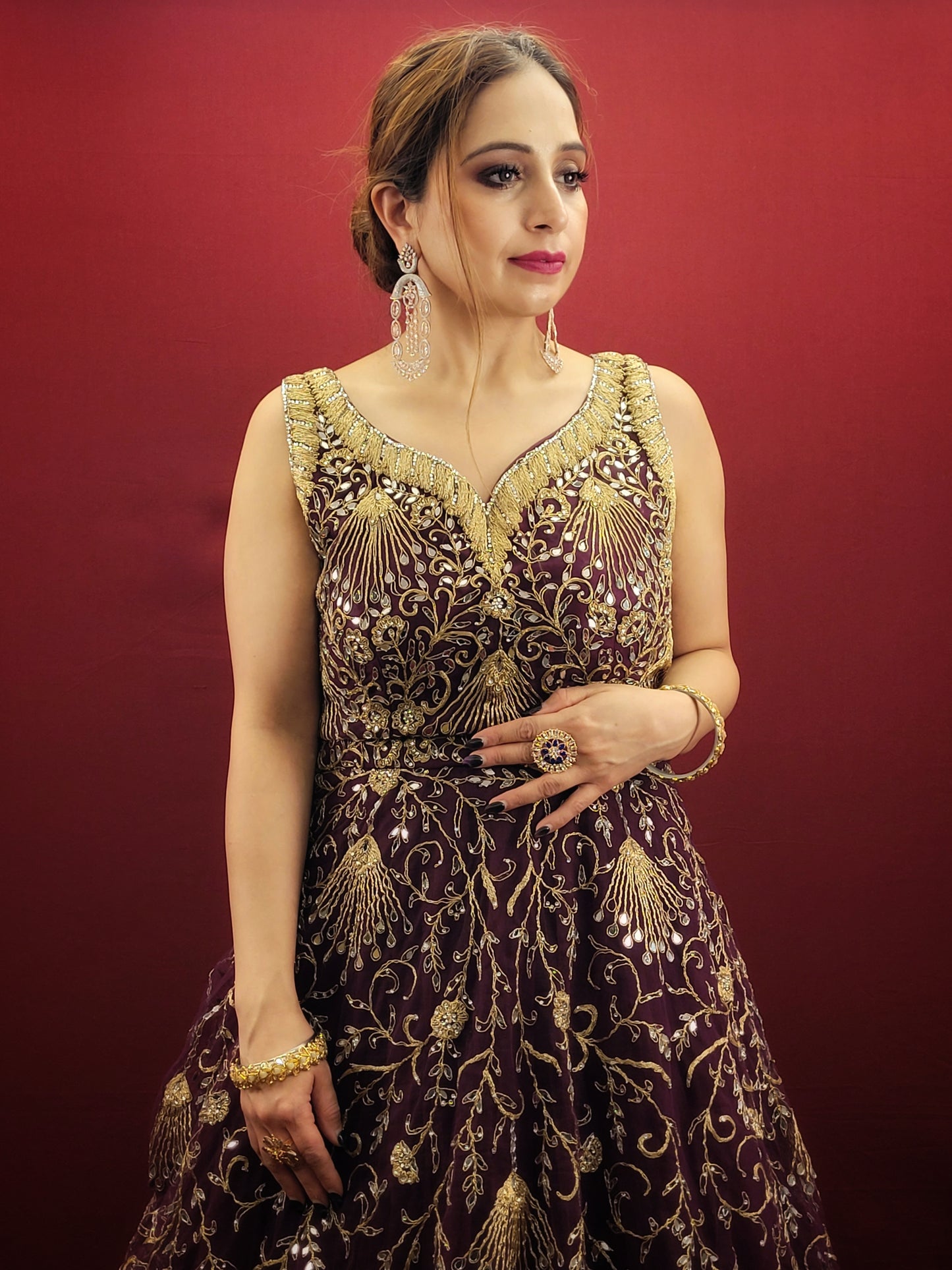 Embrace the elegance of a wine-colored gown, lavishly embellished with zari, dori and mirror work, ideal for makin a statement at engagement events and wedding parties.