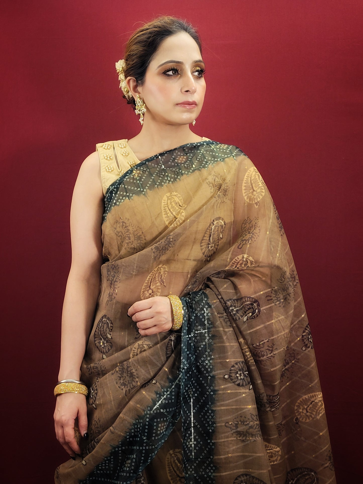 Step into the spotlight with a golden and green saree, featuring a bandhini print pallu on sheer organza, a stunning ensemble for any party or festive event.