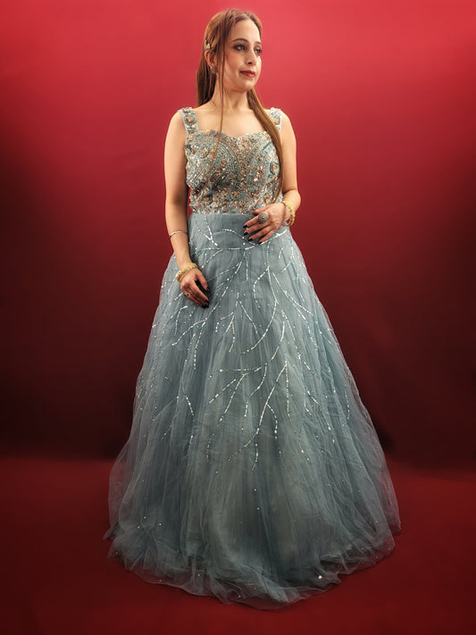This mesmerizing net gown is a dream come true for any engagement or party. The fabric drapes beautifully, accentuated by a stunning half-baked cyan blue that flatters all skin tones. Intricate sequin and beadwork adds a touch of glamour, making this gown perfect for a night to remember.