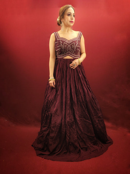 Make a lasting impression in this captivating wine chinnon gown, perfect for your own engagement or reception, or as a stunning bridesmaid dress for your sister's or friend's wedding. The intricate glass bead handwork on the choli adds a touch of elegance and shimmer, while the crushed flared lower portion creates a gracefully voluminous silhouette.