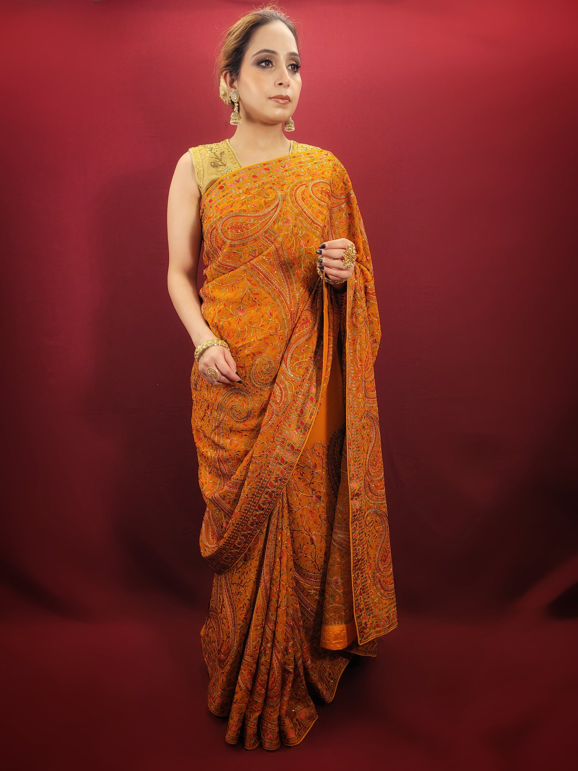 Adorn a mustard yellow georgette saree with exquisite kashmiri thread work, a versatile piece that transitions seamlessly from party wear to Puja wear.