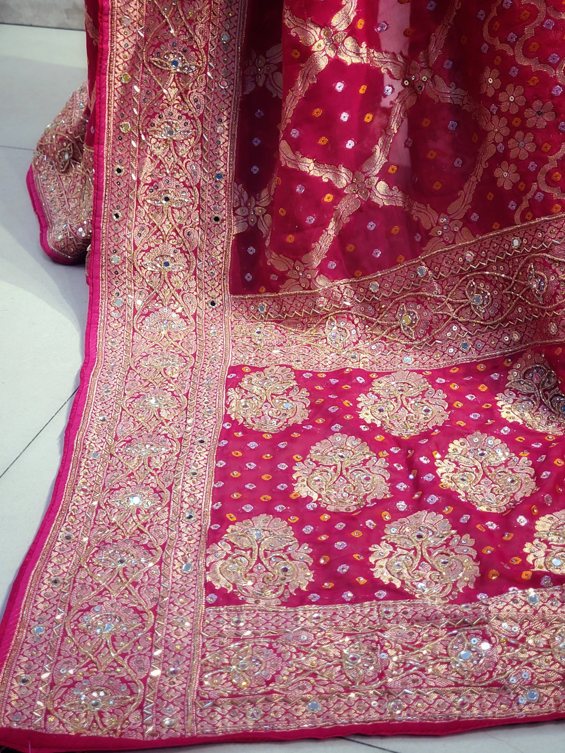 Rani Pink Georgette Banarasi (Khaddi) Bandhni Handwork Saree. Cutdana, Mirror and Sequins highlighting work. Matching unstitched blouse piece included.