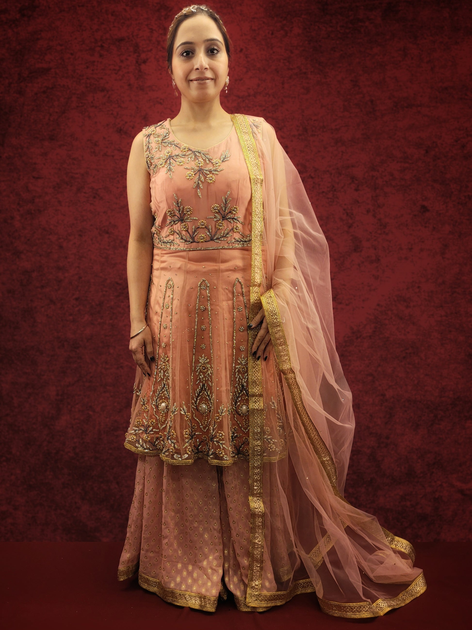 A pink indo-western ensemble featuring a net peplum top adorned with zarkan and beads, paired with a luxurious khaddi banarsi gharara, exudes a blend of contemporary flair and classic elegance.