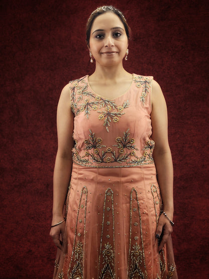 A pink indo-western ensemble featuring a net peplum top adorned with zarkan and beads, paired with a luxurious khaddi banarsi gharara, exudes a blend of contemporary flair and classic elegance.