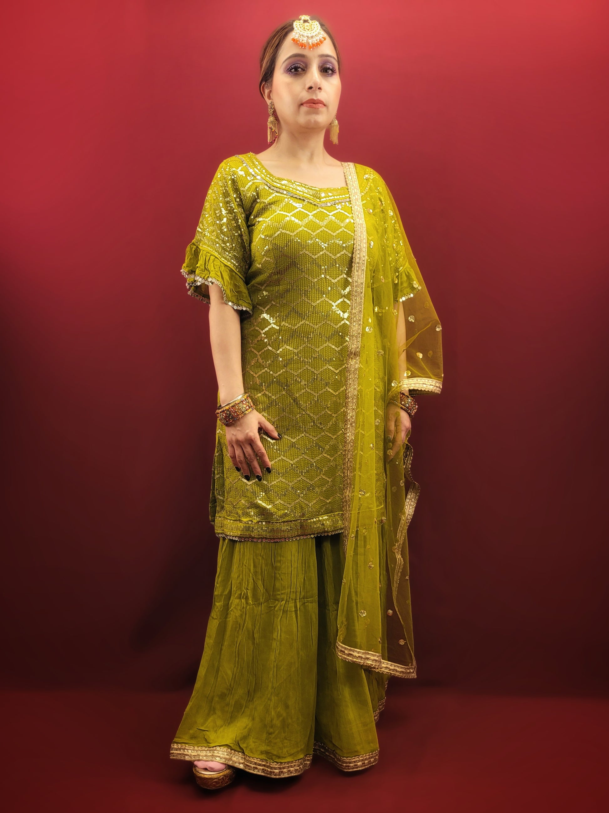 Embrace elegance with a mehendi green sharara set, featuring a dazzling sequins work and a beads & zari embellished neckline, crafted from luxurious chinnon fabric for a quintessential Indian ethnic wear ensemble.