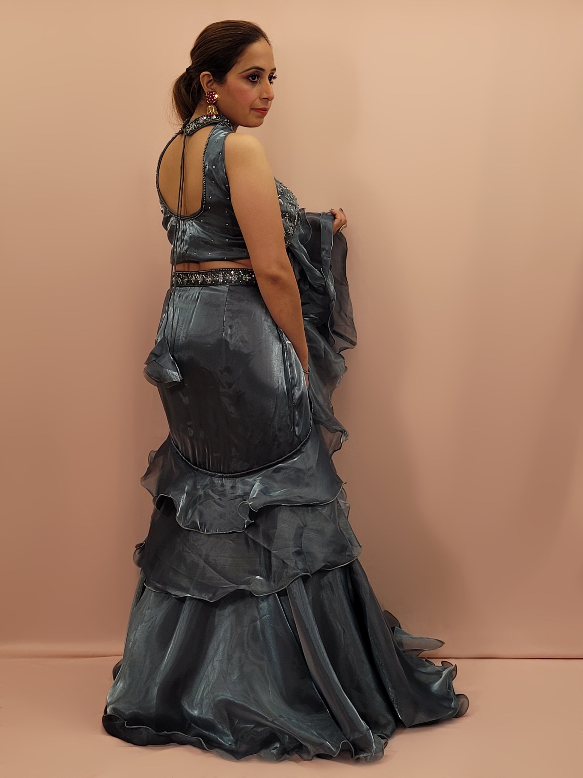 Elevate your ethnic wardrobe with this stunning Steel Blue Ready to Wear Drape Saree, crafted from luxurious Jimmy Choo fabric. This exquisite saree features a fish cut mermaid style skirt that beautifully accentuates your silhouette, flowing into a flared hem for a dramatic effect. The ensemble is completed with a hand work blouse, intricately adorned with shimmering sequins and delicate beads, adding a touch of glamour to your look.