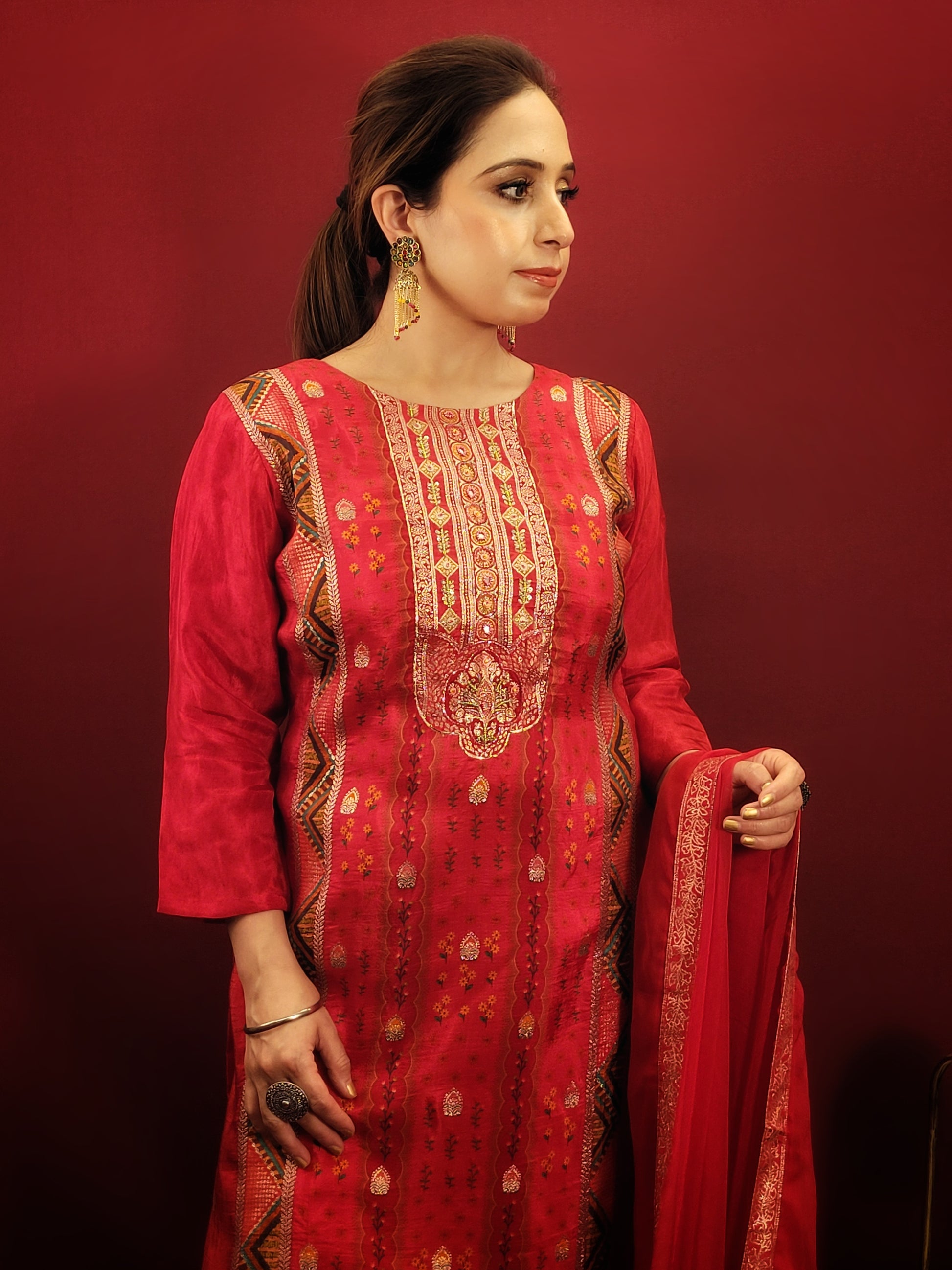 Add a touch of timeless elegance to your ethnic wear collection with this stunning red kurti pant dupatta set. The kurti boasts a beautiful multicolored Banarasi weave, intricately detailed with handwork that speaks volumes of Indian craftsmanship. Made from soft and breathable muslin, the kurti drapes beautifully, while the contrasting chiffon dupatta adds a touch of flowy grace.