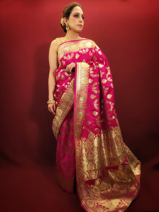 A magenta pink banarasi saree, adorned with handloom woven zari, exudes timeless elegance, perfect for wedding and reception wear.