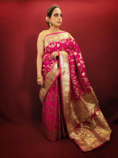 A magenta pink banarasi saree, adorned with handloom woven zari, exudes timeless elegance, perfect for wedding and reception wear.