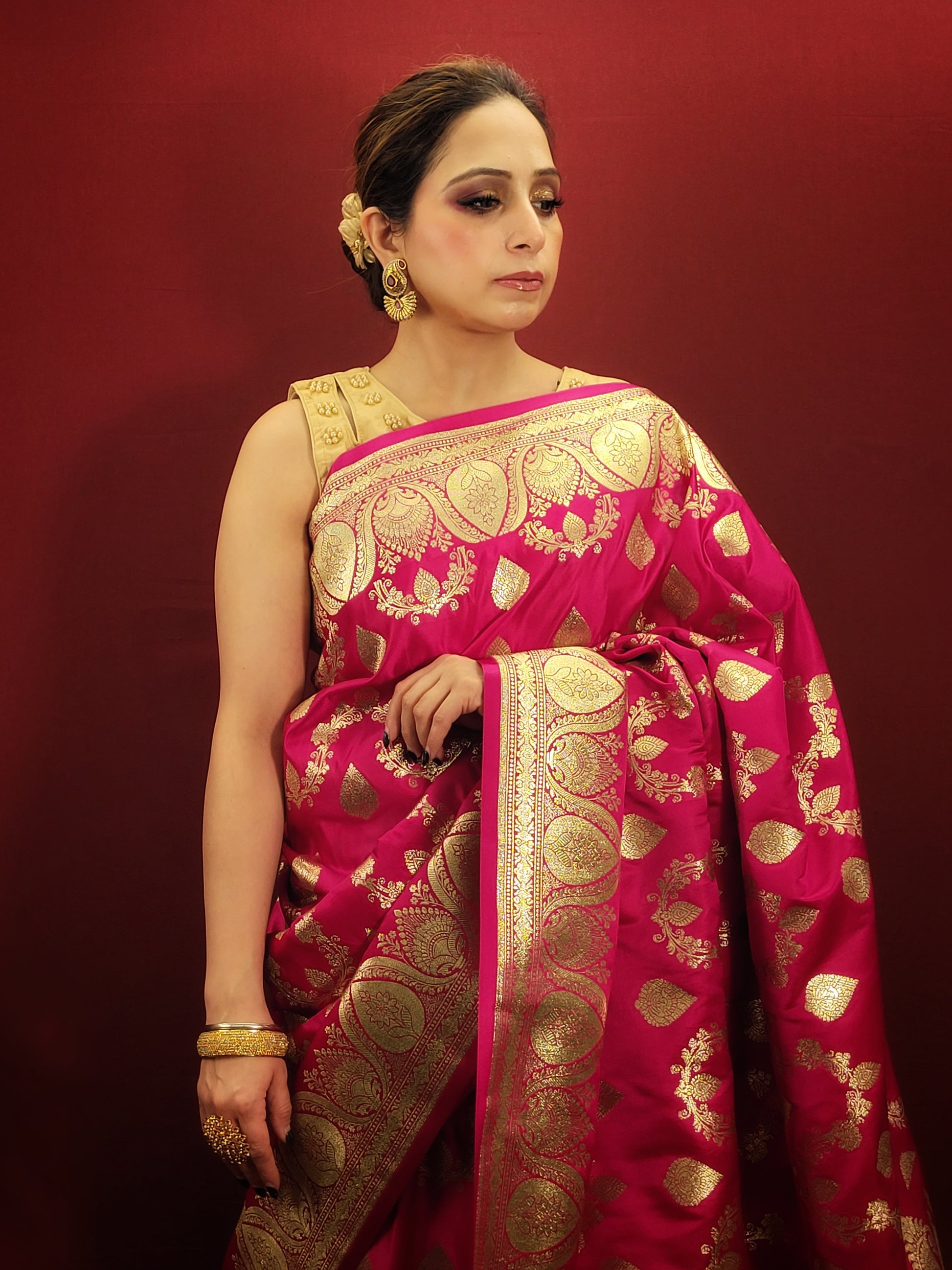 A magenta pink banarasi saree, adorned with handloom woven zari, exudes timeless elegance, perfect for wedding and reception wear.