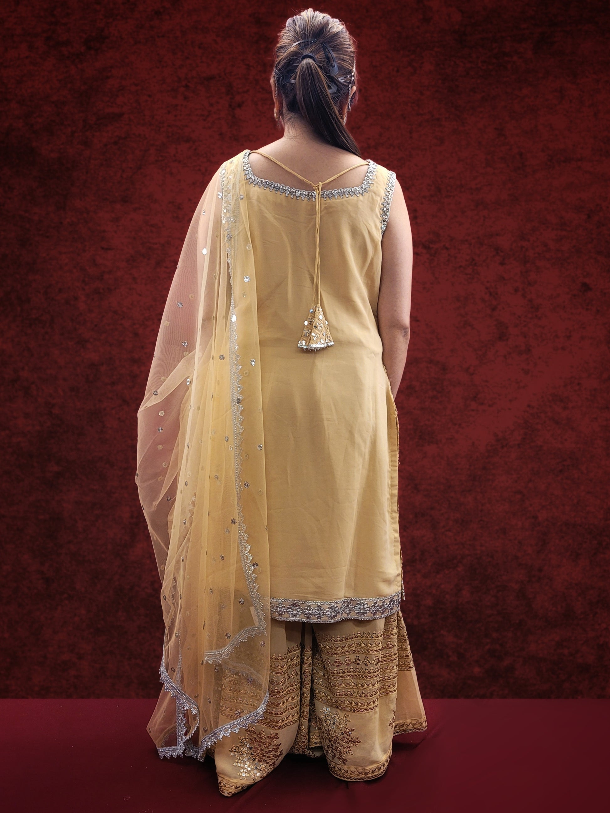 Embrace elegance with a golden beige kameez adorned with delicate sequins and thread work, paired with a gharara, for a stunning ethnic wear ensemble, ideal for party and festive occasions.