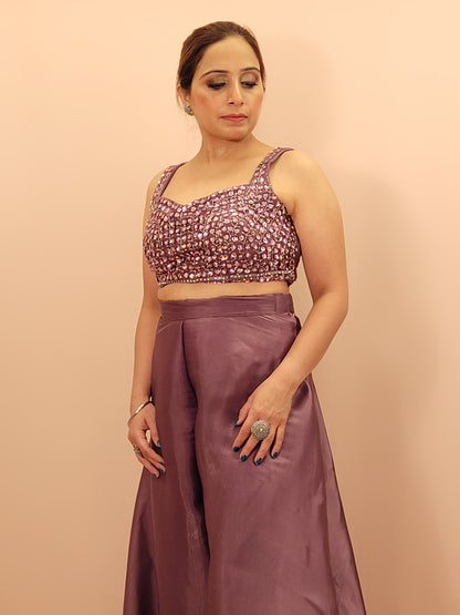 levate your festive wardrobe with our Mauve Shimmer Pallazo Top Indowestern Fusion Set - a perfect blend of tradition and modernity. This stunning ensemble features a sleeveless cropped blouse adorned with exquisite beadwork and sparkling sequins that catch the light beautifully. Paired with a high-waisted, flowing Pallazo in luxurious grey Jimmy Choo fabric, this outfit promises an elegant silhouette and timeless grace.