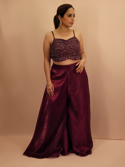 Elevate your festive wardrobe with our Maroon Shimmer Pallazo Top Indowestern Fusion Set - a perfect blend of tradition and modernity. This stunning ensemble features a sleeveless cropped blouse adorned with exquisite beadwork and sparkling sequins that catch the light beautifully. Paired with a high-waisted, flowing Pallazo in luxurious Maroon Jimmy Choo fabric, this outfit promises an elegant silhouette and timeless grace. Ideal for weddings, celebrations, or any special event
