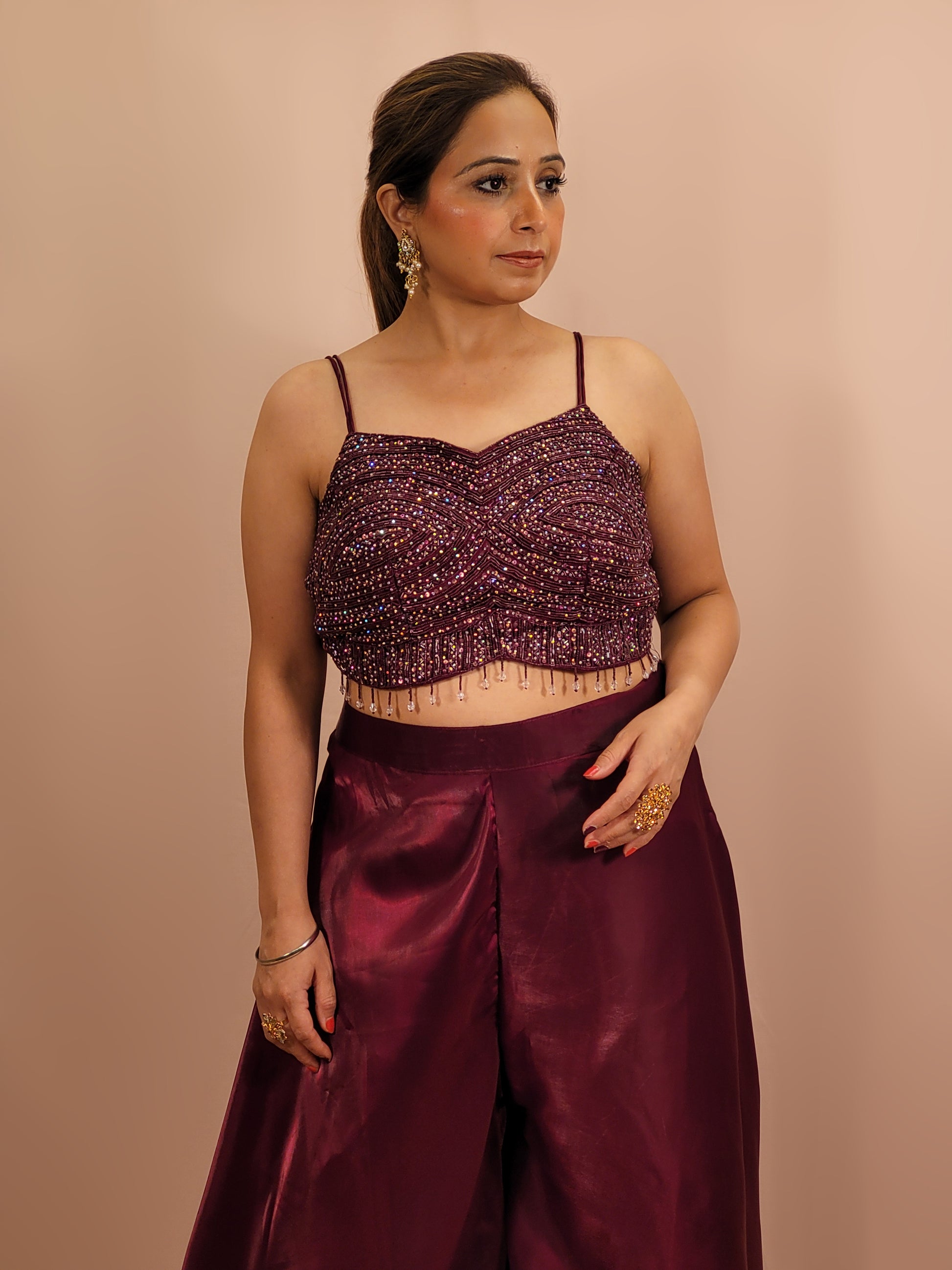 Elevate your festive wardrobe with our Maroon Shimmer Pallazo Top Indowestern Fusion Set - a perfect blend of tradition and modernity. This stunning ensemble features a sleeveless cropped blouse adorned with exquisite beadwork and sparkling sequins that catch the light beautifully. Paired with a high-waisted, flowing Pallazo in luxurious Maroon Jimmy Choo fabric, this outfit promises an elegant silhouette and timeless grace. Ideal for weddings, celebrations, or any special event