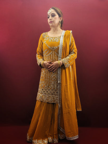 A mustard yellow georgette kameez gharara set, embellished with sparkling zarkan and zardozi work, radiates traditional charm, perfect for bridal and wedding attire.