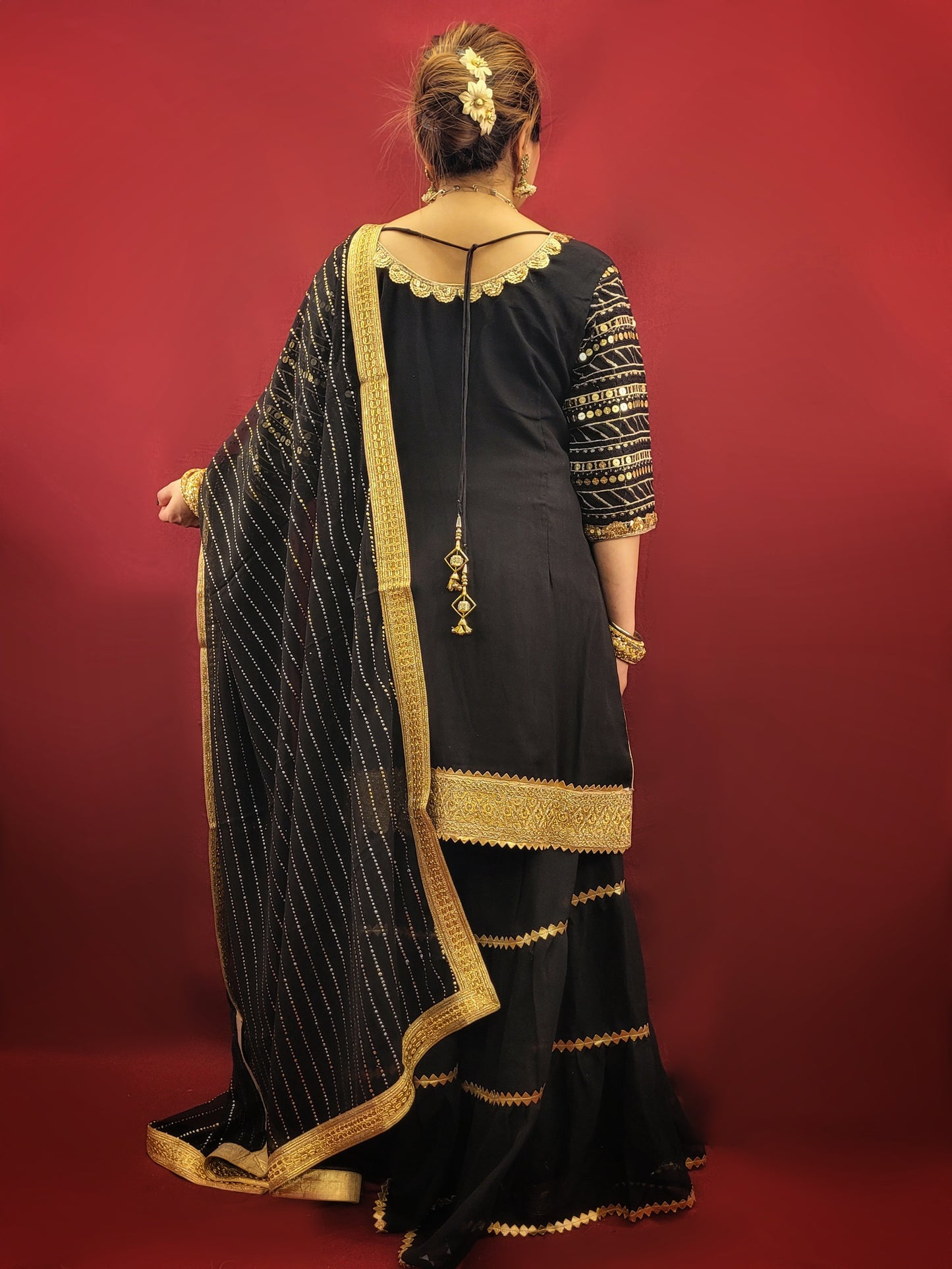 This black kameez and sharara set with sequins is perfect for a variety of occasions, from festive celebrations, to wedding events, making it a versatile choice for those seeking a blend of traditional and indo-western ethnic wear. It is ideal for adding a touch of glamour to any special occasion.