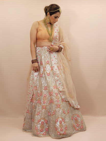 Elevate your ethnic wardrobe with this stunning ivory-colored net unstitched lehenga, a perfect blend of traditional craftsmanship and contemporary elegance. This lehenga is intricately adorned with shimmering water sequins and delicate glass beads work, creating a mesmerizing effect that catches the light with every movement.