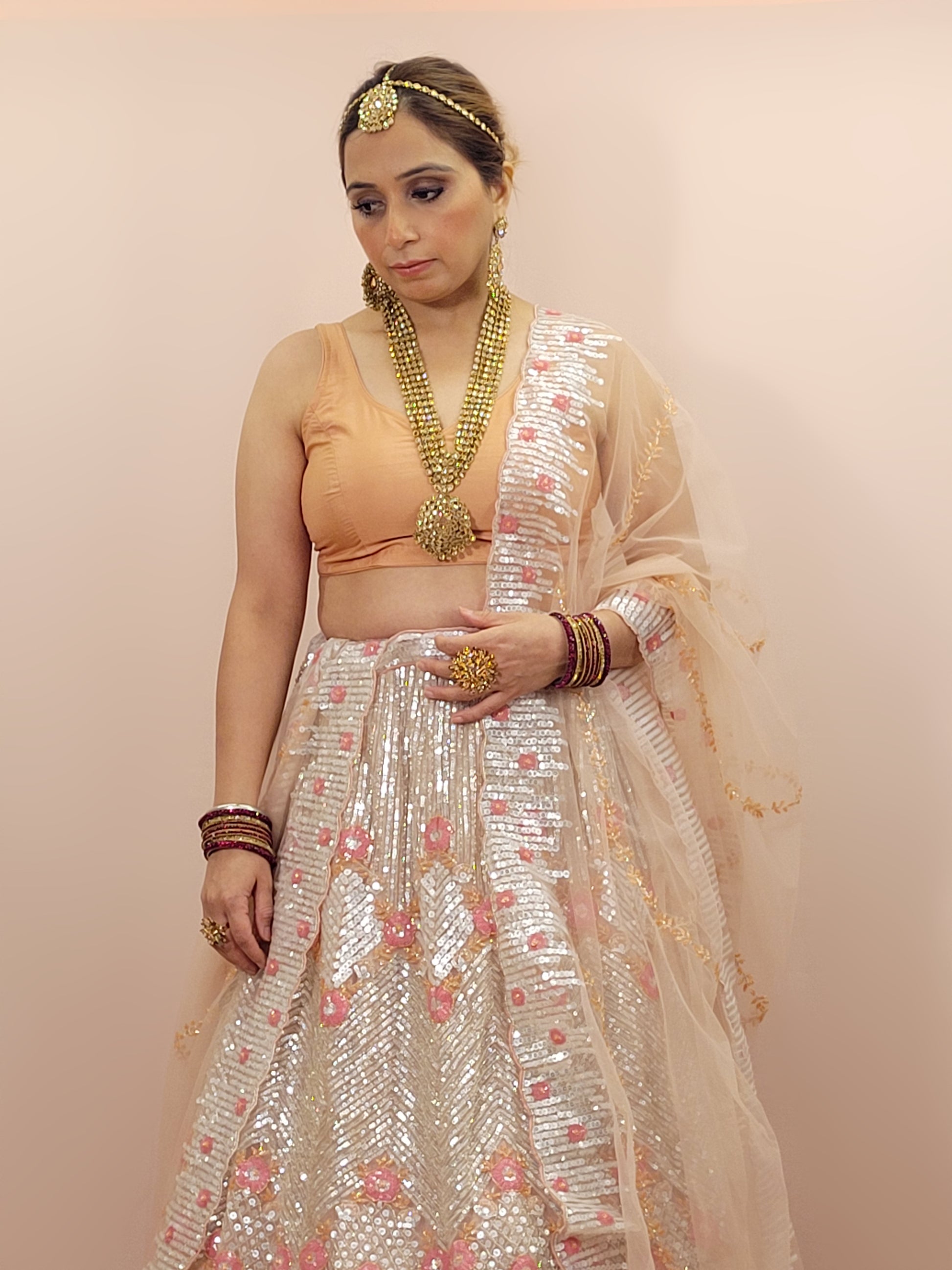 Elevate your ethnic wardrobe with this stunning ivory-colored net unstitched lehenga, a perfect blend of traditional craftsmanship and contemporary elegance. This lehenga is intricately adorned with shimmering water sequins and delicate glass beads work, creating a mesmerizing effect that catches the light with every movement.