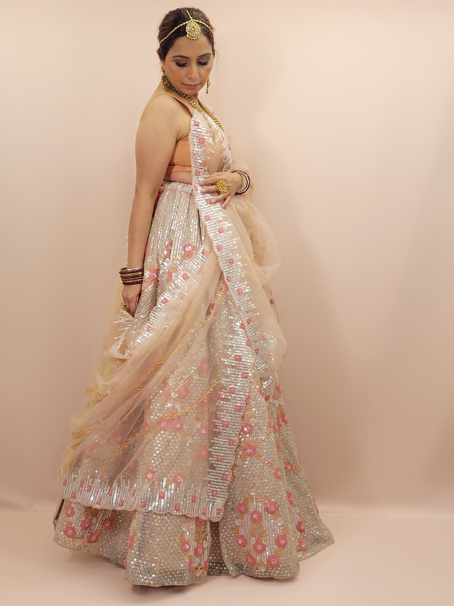 Elevate your ethnic wardrobe with this stunning ivory-colored net unstitched lehenga, a perfect blend of traditional craftsmanship and contemporary elegance. This lehenga is intricately adorned with shimmering water sequins and delicate glass beads work, creating a mesmerizing effect that catches the light with every movement.