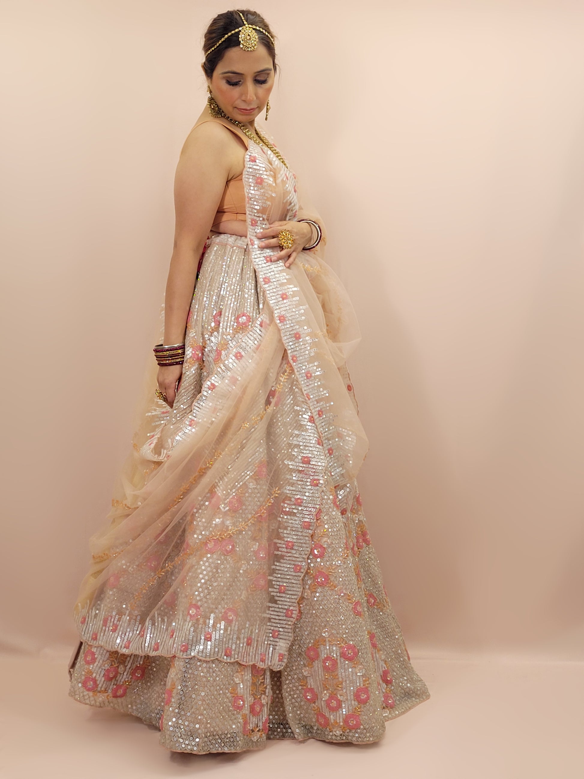 Elevate your ethnic wardrobe with this stunning ivory-colored net unstitched lehenga, a perfect blend of traditional craftsmanship and contemporary elegance. This lehenga is intricately adorned with shimmering water sequins and delicate glass beads work, creating a mesmerizing effect that catches the light with every movement.