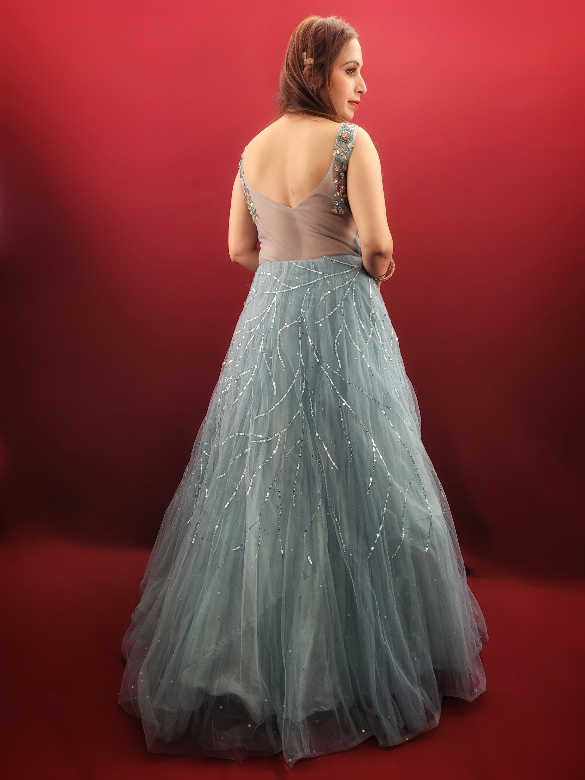 This mesmerizing net gown is a dream come true for any engagement or party. The fabric drapes beautifully, accentuated by a stunning half-baked cyan blue that flatters all skin tones. Intricate sequin and beadwork adds a touch of glamour, making this gown perfect for a night to remember.