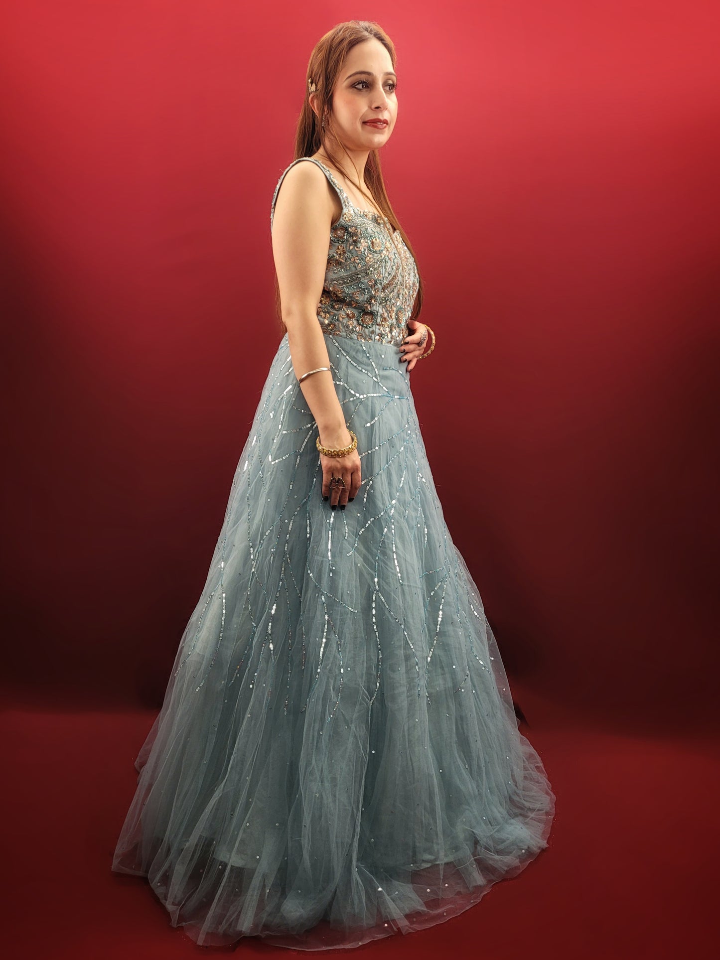 This mesmerizing net gown is a dream come true for any engagement or party. The fabric drapes beautifully, accentuated by a stunning half-baked cyan blue that flatters all skin tones. Intricate sequin and beadwork adds a touch of glamour, making this gown perfect for a night to remember.