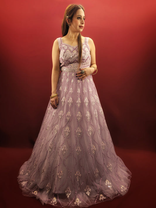 Be the star of your own fairytale with this mesmerizing Lavender Net Gown. Crafted from layers of light-as-air net, this gown drapes effortlessly, creating a silhouette that is both romantic and undeniably glamorous. Prepare to be swept away by the exquisite embellishments adorning this captivating piece.