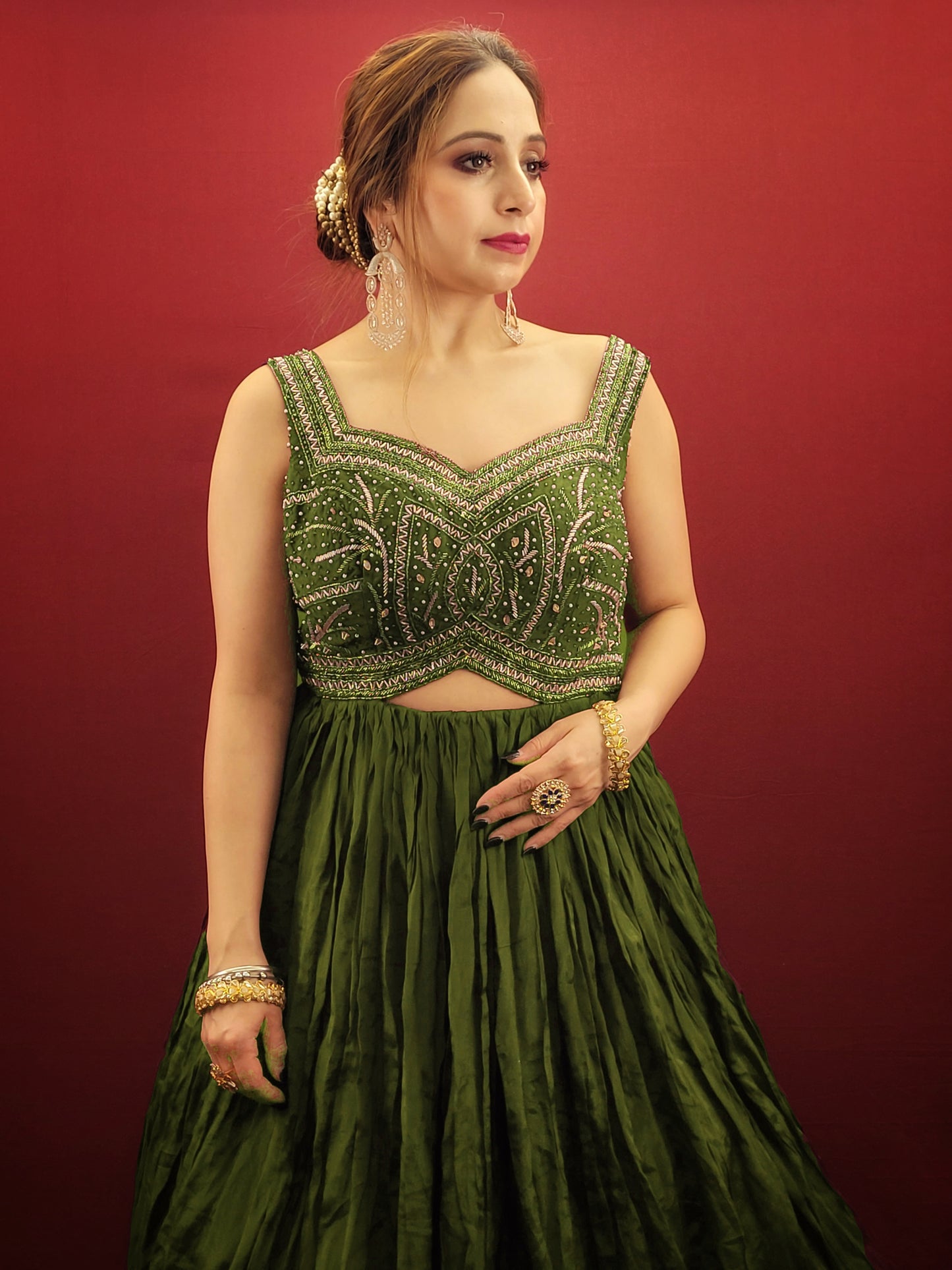 Make a lasting impression in this captivating mehendi green chinnon gown, perfect for your own engagement or reception, or as a stunning bridesmaid dress for your sister's or friend's wedding. The intricate glass bead handwork on the choli adds a touch of elegance and shimmer, while the crushed flared lower portion creates a gracefully voluminous silhouette.