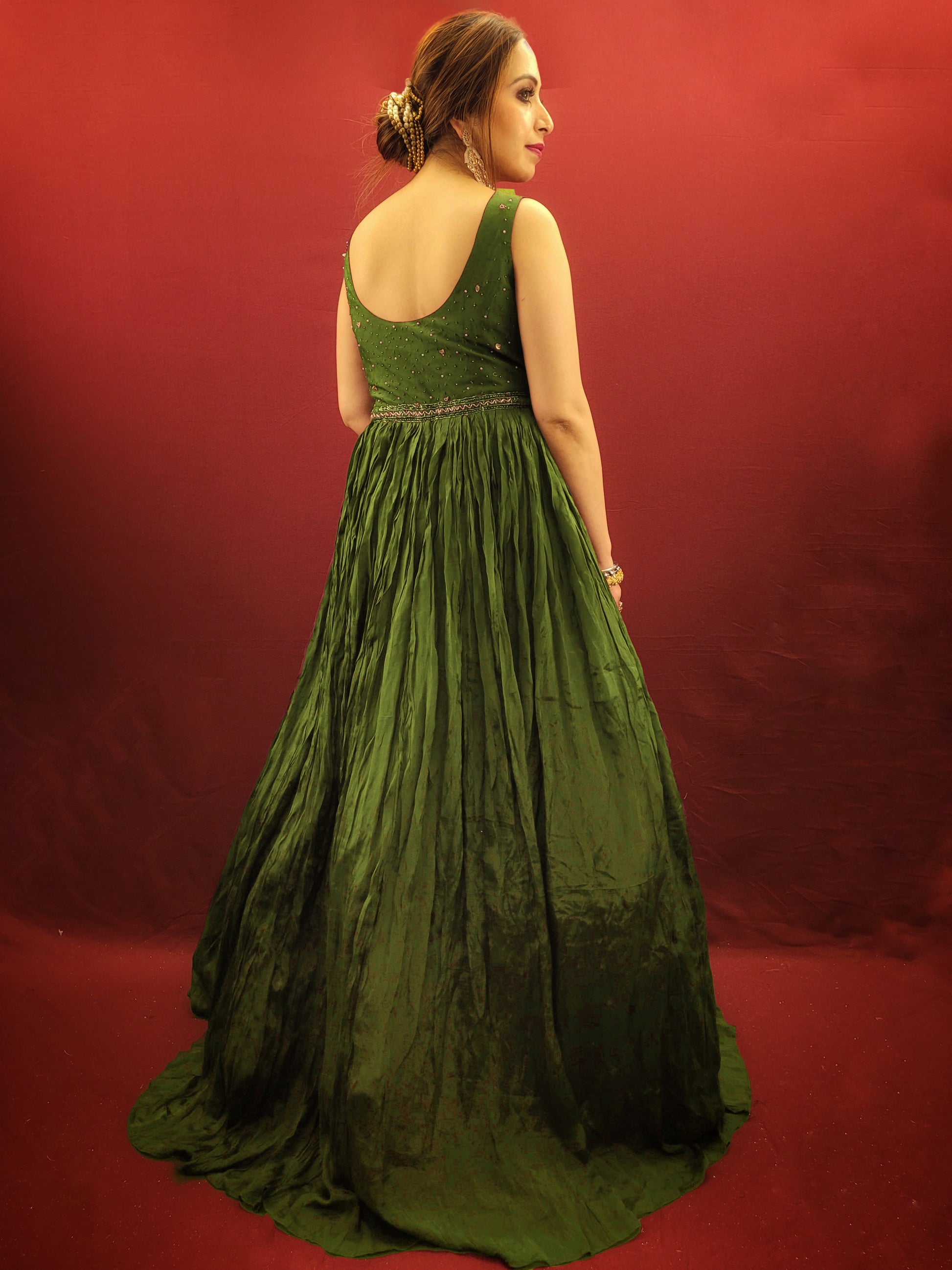 Make a lasting impression in this captivating mehendi green chinnon gown, perfect for your own engagement or reception, or as a stunning bridesmaid dress for your sister's or friend's wedding. The intricate glass bead handwork on the choli adds a touch of elegance and shimmer, while the crushed flared lower portion creates a gracefully voluminous silhouette.