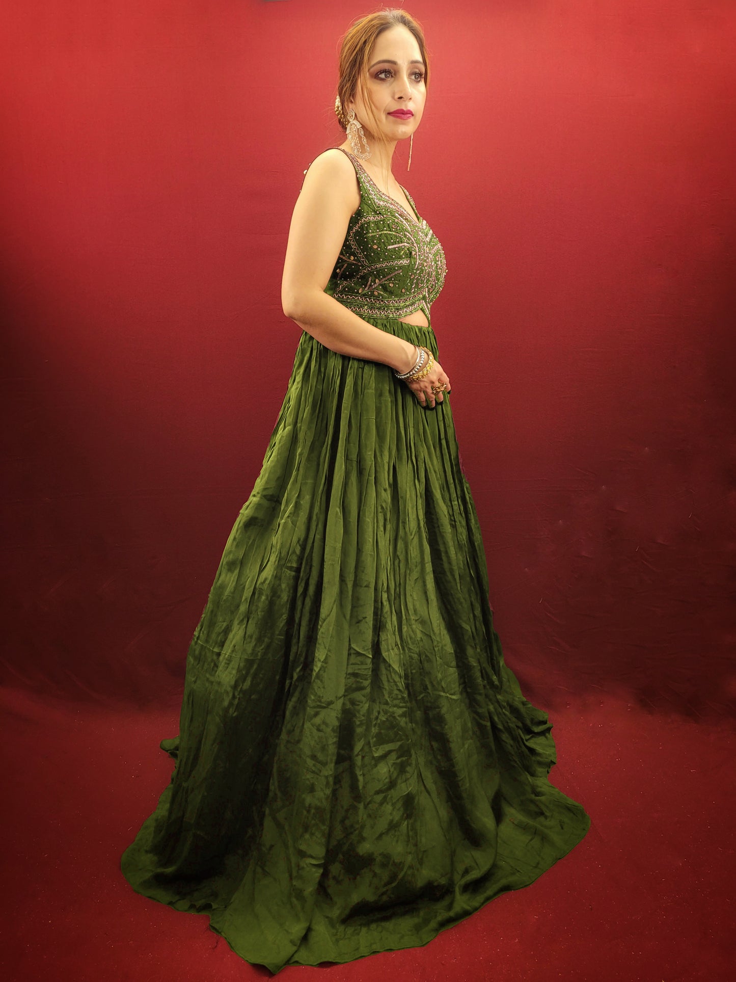 Make a lasting impression in this captivating mehendi green chinnon gown, perfect for your own engagement or reception, or as a stunning bridesmaid dress for your sister's or friend's wedding. The intricate glass bead handwork on the choli adds a touch of elegance and shimmer, while the crushed flared lower portion creates a gracefully voluminous silhouette.