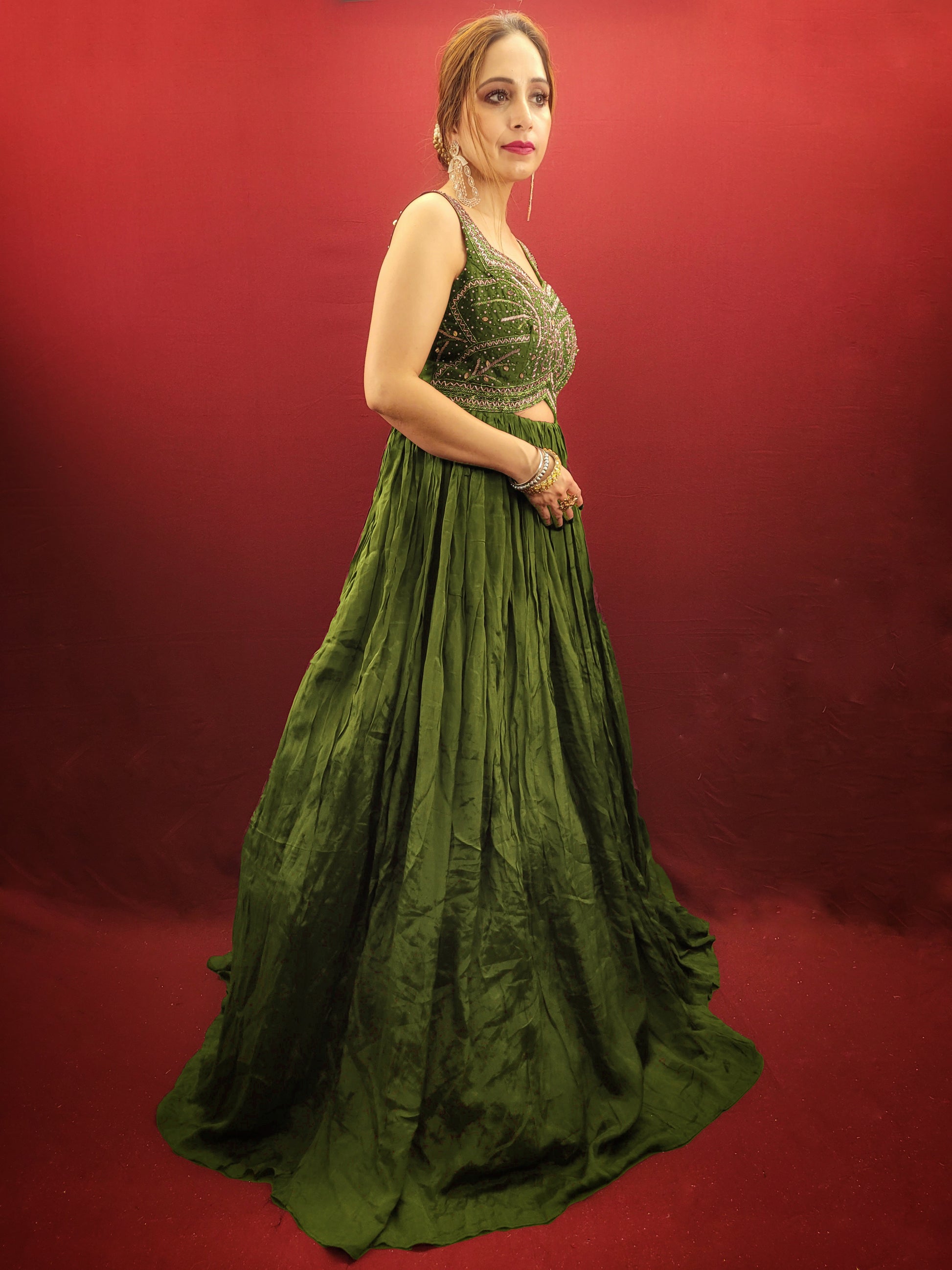 Make a lasting impression in this captivating mehendi green chinnon gown, perfect for your own engagement or reception, or as a stunning bridesmaid dress for your sister's or friend's wedding. The intricate glass bead handwork on the choli adds a touch of elegance and shimmer, while the crushed flared lower portion creates a gracefully voluminous silhouette.