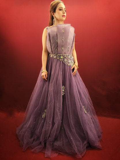 Embrace a look that's both romantic and unforgettable in this opera mauve net gown. The luxurious net fabric cascades down your figure, creating a silhouette that's both soft and ethereal. The true star of the show, however, is the 3D sculpted organza bodice.