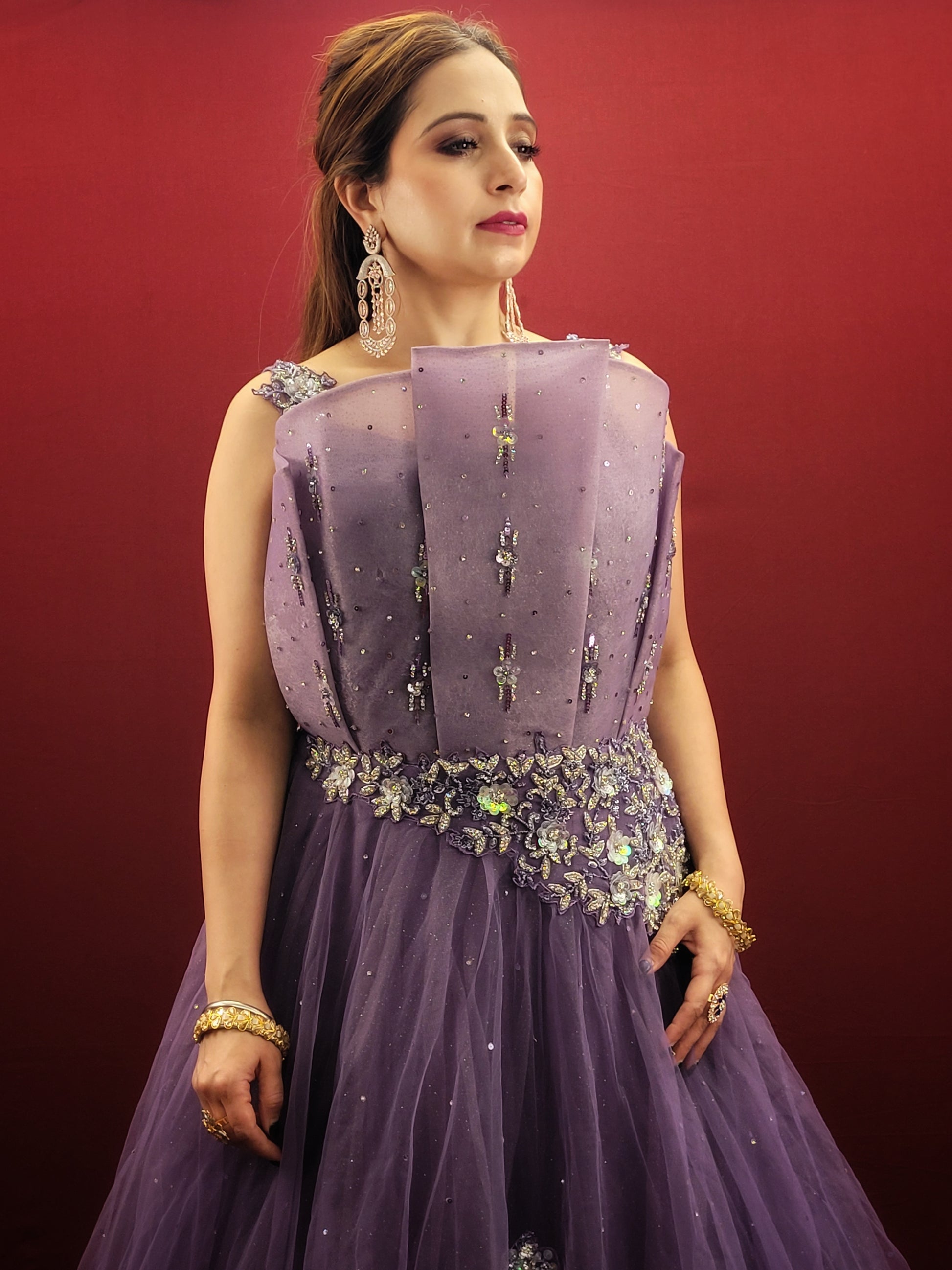 Embrace a look that's both romantic and unforgettable in this opera mauve net gown. The luxurious net fabric cascades down your figure, creating a silhouette that's both soft and ethereal. The true star of the show, however, is the 3D sculpted organza bodice.