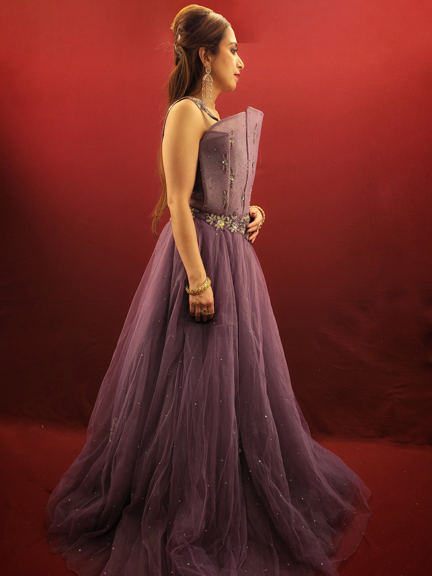 Embrace a look that's both romantic and unforgettable in this opera mauve net gown. The luxurious net fabric cascades down your figure, creating a silhouette that's both soft and ethereal. The true star of the show, however, is the 3D sculpted organza bodice.