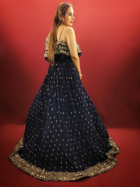 Embrace a captivating silhouette in this stunning navy blue georgette gown. The luxurious fabric drapes elegantly, offering both comfort and a touch of sophistication. The eye-catching one-shoulder design adds a touch of modern allure, while the layered bodice takes center stage with a dazzling display of craftsmanship.