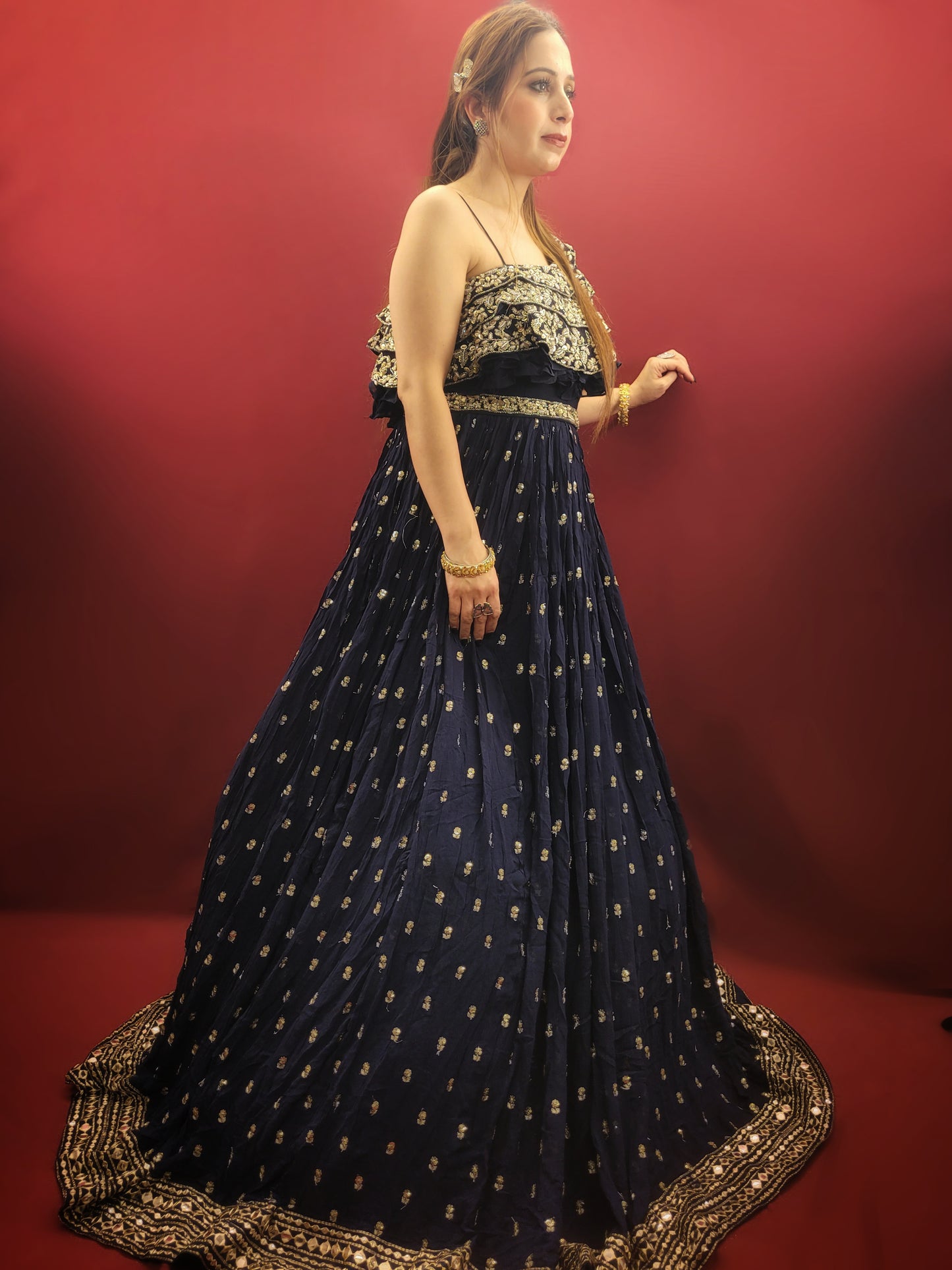Embrace a captivating silhouette in this stunning navy blue georgette gown. The luxurious fabric drapes elegantly, offering both comfort and a touch of sophistication. The eye-catching one-shoulder design adds a touch of modern allure, while the layered bodice takes center stage with a dazzling display of craftsmanship.