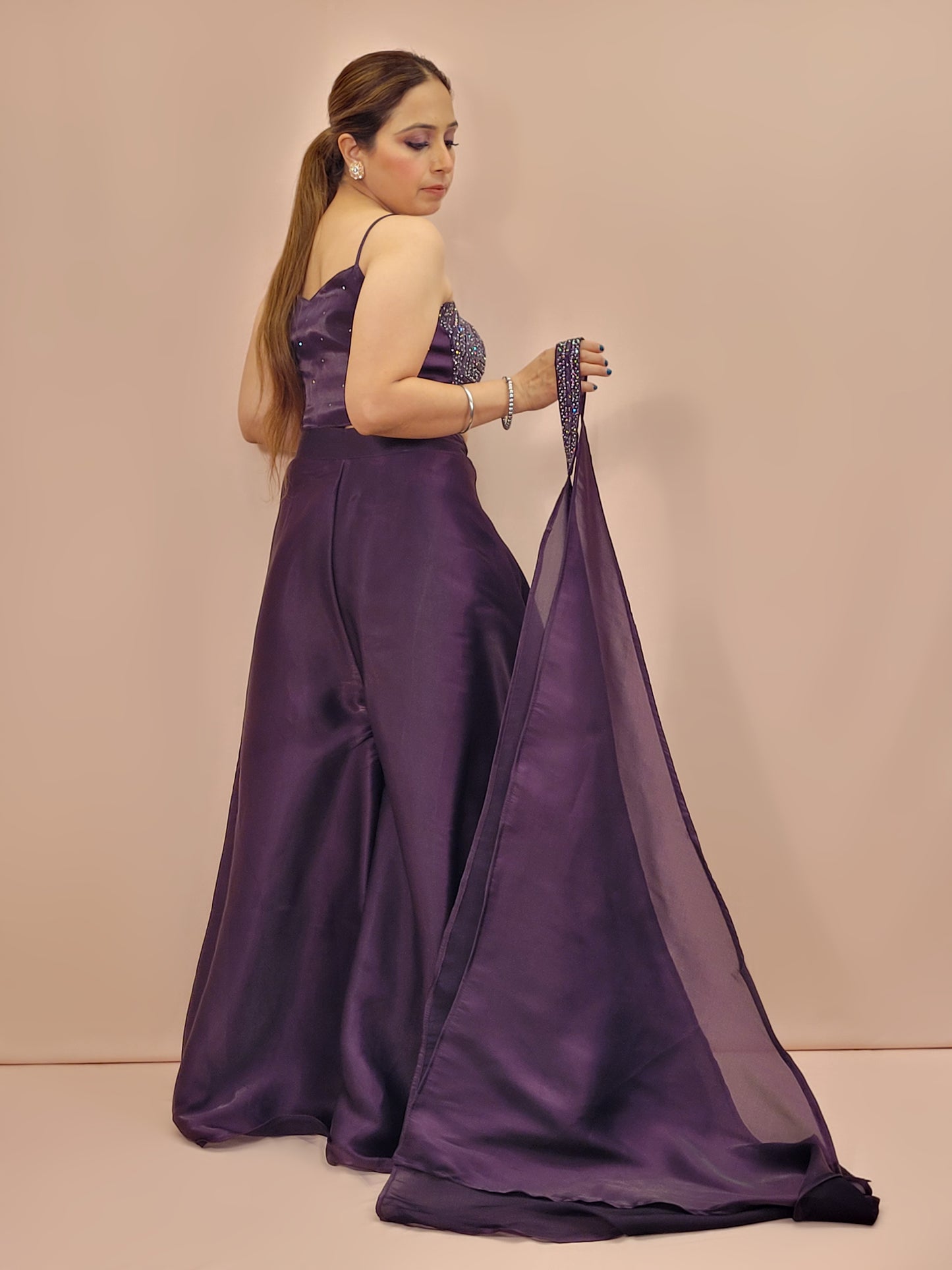 Elevate your festive wardrobe with our Purple Shimmer Pallazo Top Indowestern Fusion Set - a perfect blend of tradition and modernity. This stunning ensemble features a sleeveless cropped blouse adorned with exquisite beadwork and sparkling sequins that catch the light beautifully. Paired with a high-waisted, flowing Pallazo in luxurious Purple Jimmy Choo fabric, this outfit promises an elegant silhouette and timeless grace. Ideal for weddings, celebrations, or any special event