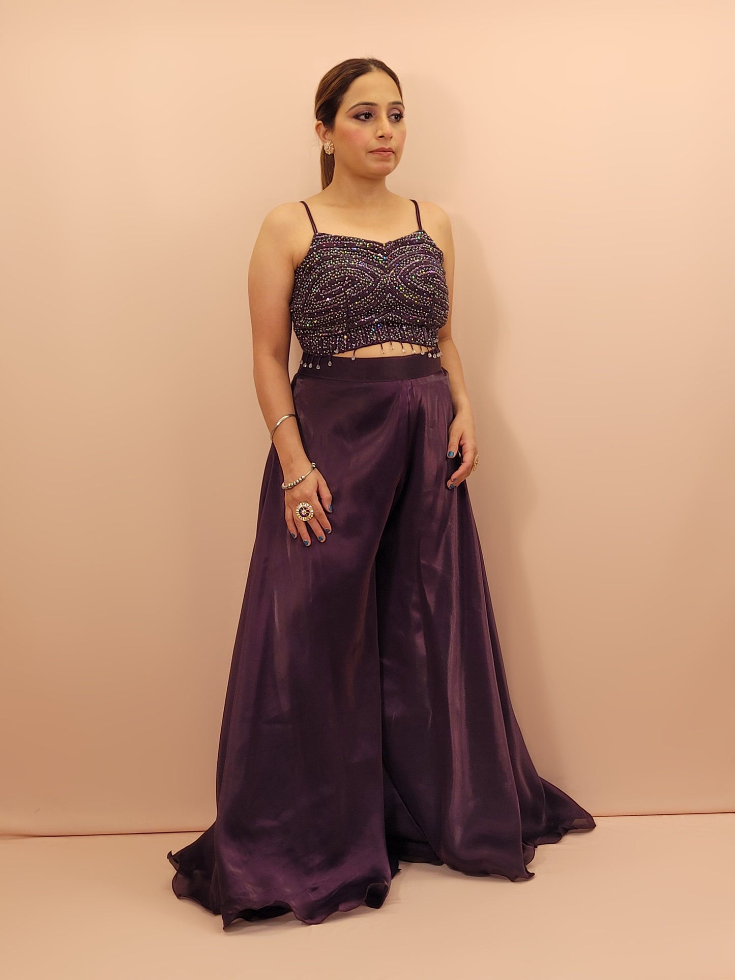 Elevate your festive wardrobe with our Purple Shimmer Pallazo Top Indowestern Fusion Set - a perfect blend of tradition and modernity. This stunning ensemble features a sleeveless cropped blouse adorned with exquisite beadwork and sparkling sequins that catch the light beautifully. Paired with a high-waisted, flowing Pallazo in luxurious Purple Jimmy Choo fabric, this outfit promises an elegant silhouette and timeless grace. Ideal for weddings, celebrations, or any special event