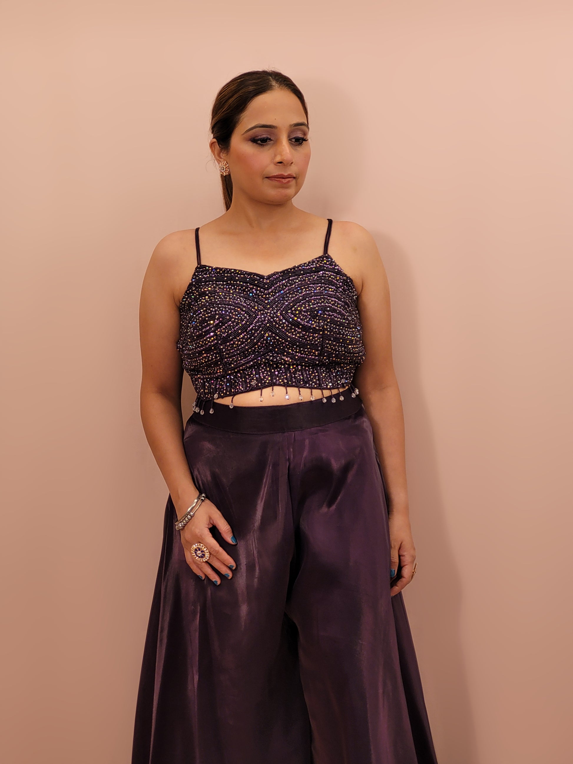 Elevate your festive wardrobe with our Purple Shimmer Pallazo Top Indowestern Fusion Set - a perfect blend of tradition and modernity. This stunning ensemble features a sleeveless cropped blouse adorned with exquisite beadwork and sparkling sequins that catch the light beautifully. Paired with a high-waisted, flowing Pallazo in luxurious Purple Jimmy Choo fabric, this outfit promises an elegant silhouette and timeless grace. Ideal for weddings, celebrations, or any special event