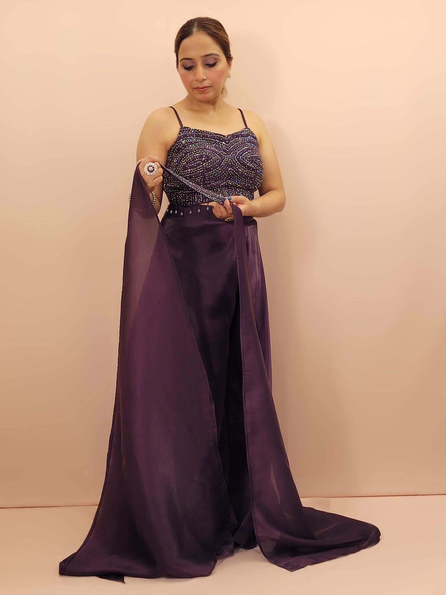 Elevate your festive wardrobe with our Purple Shimmer Pallazo Top Indowestern Fusion Set - a perfect blend of tradition and modernity. This stunning ensemble features a sleeveless cropped blouse adorned with exquisite beadwork and sparkling sequins that catch the light beautifully. Paired with a high-waisted, flowing Pallazo in luxurious Purple Jimmy Choo fabric, this outfit promises an elegant silhouette and timeless grace. Ideal for weddings, celebrations, or any special event